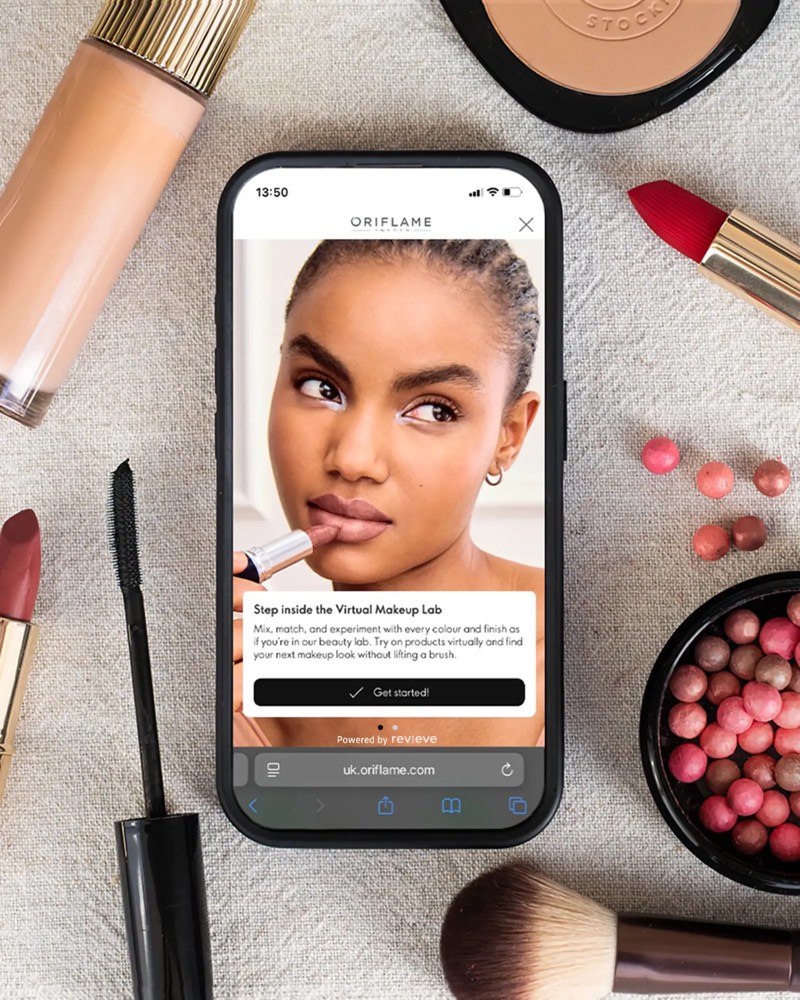 Oriflame Virtual Makeup Lab on a phone, surrounded by make-up